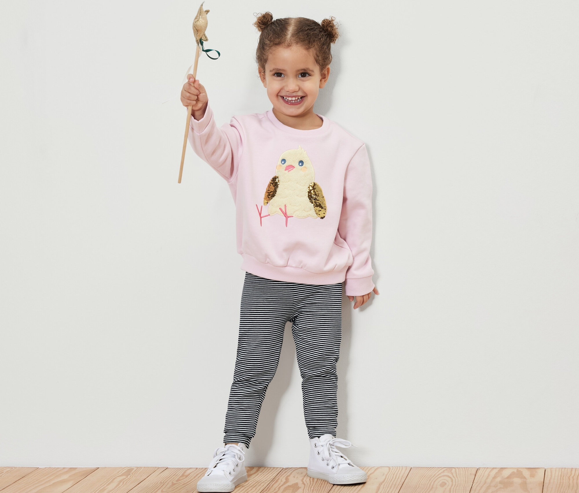 Mädchen hält ein Spielzeugvogel hoch und trägt 5 Kinder-Leggings.