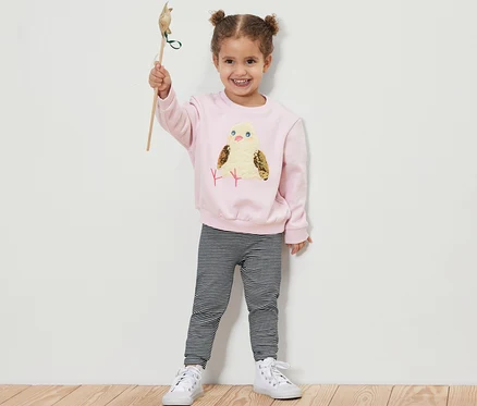 Mädchen hält ein Spielzeugvogel hoch und trägt 5 Kinder-Leggings.