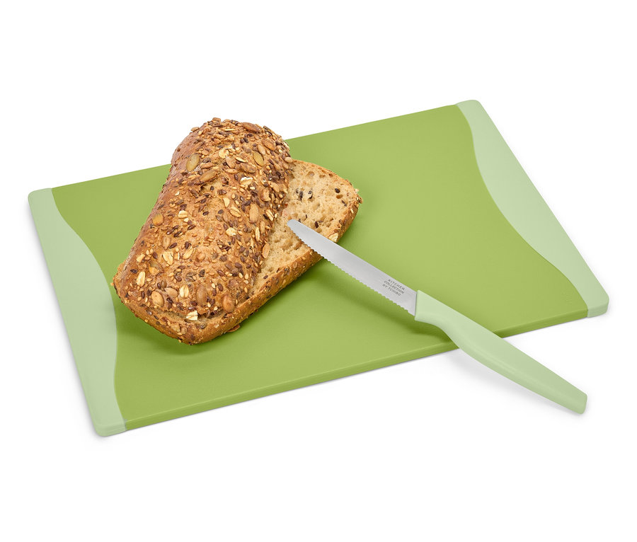 Brot und Messer auf einem grünen Schneidebrett.