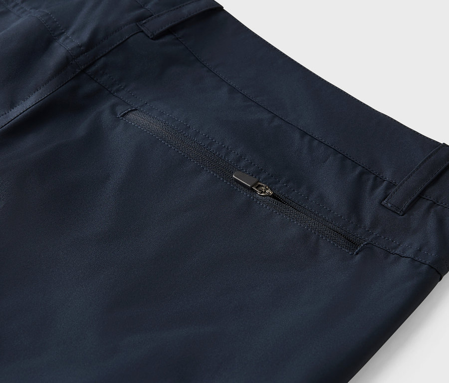 Detailaufnahme einer marineblauen Hose mit einer Reißverschlusstasche.