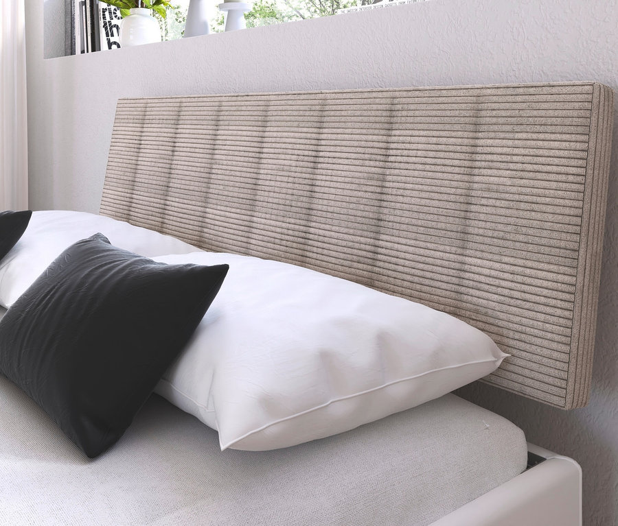 Detailansicht eines weißen Bettes mit Kissen und dem »Mavi-Extra« Bett mit Polsterkopfteil.