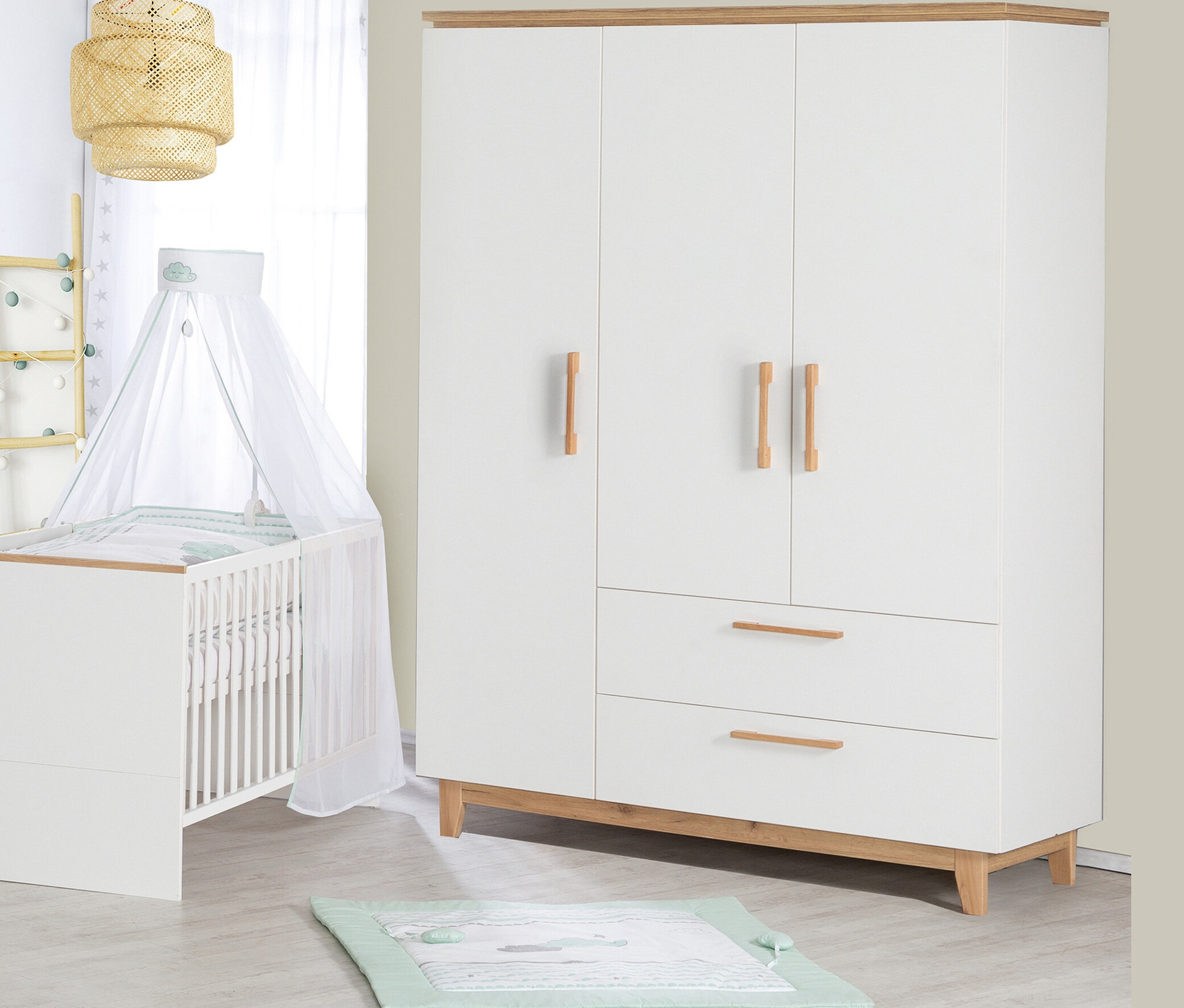 Ein Kinderzimmer mit einem weißen Kinderbett mit Himmel, einem weißen dreitürigen Kleiderschrank und einer Spieldecke auf dem Boden.