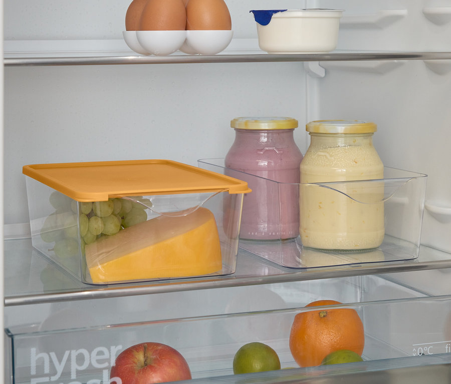 Ein Blick in einen Kühlschrank mit Lebensmitteln. Oben Eier, darunter Gläser mit Marmelade, Käse und Trauben in einem durchsichtigen Behälter.