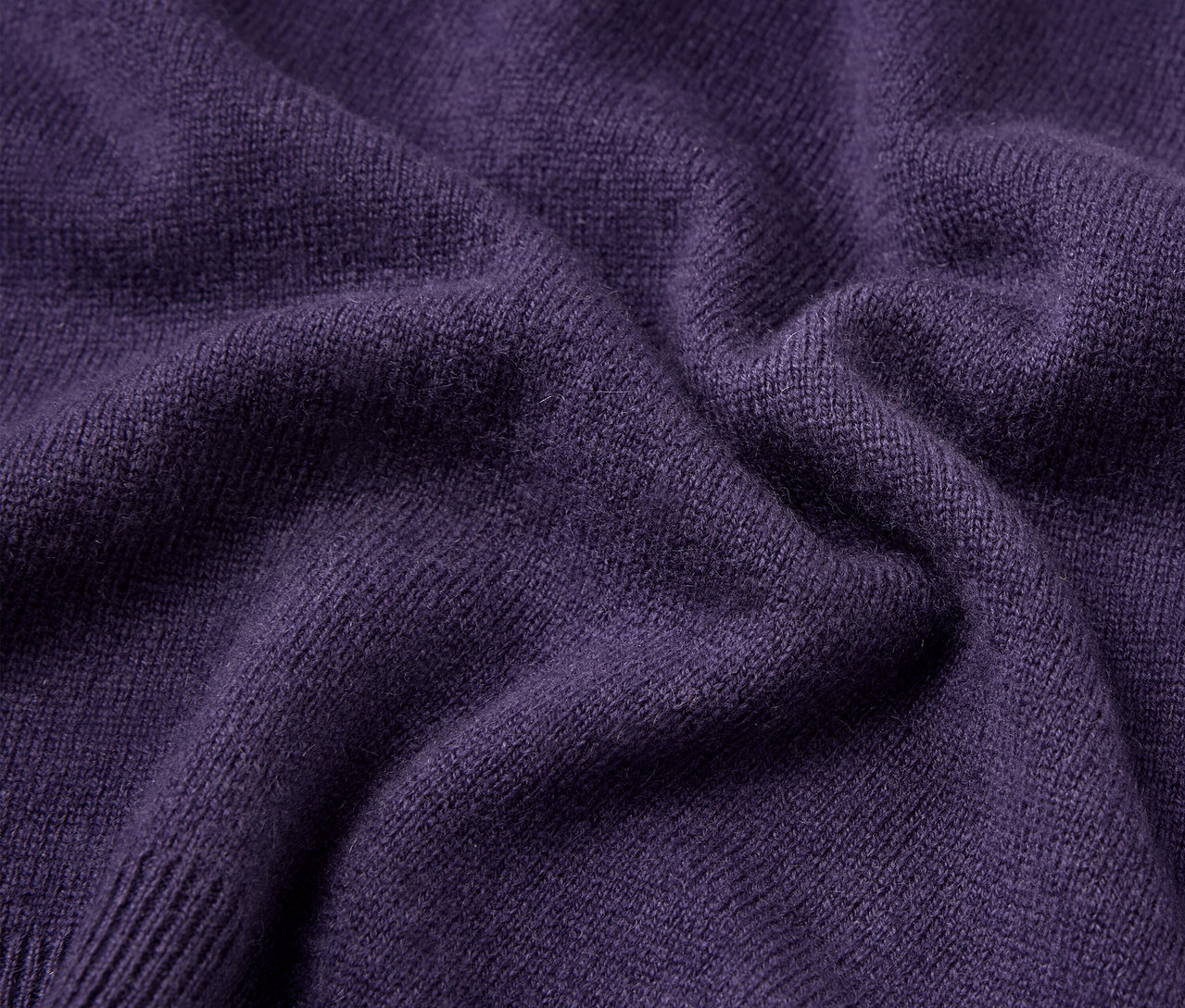 Nahaufnahme der Textur eines lila Pullovers.