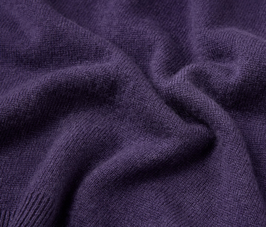 Nahaufnahme der Textur eines lila Pullovers.