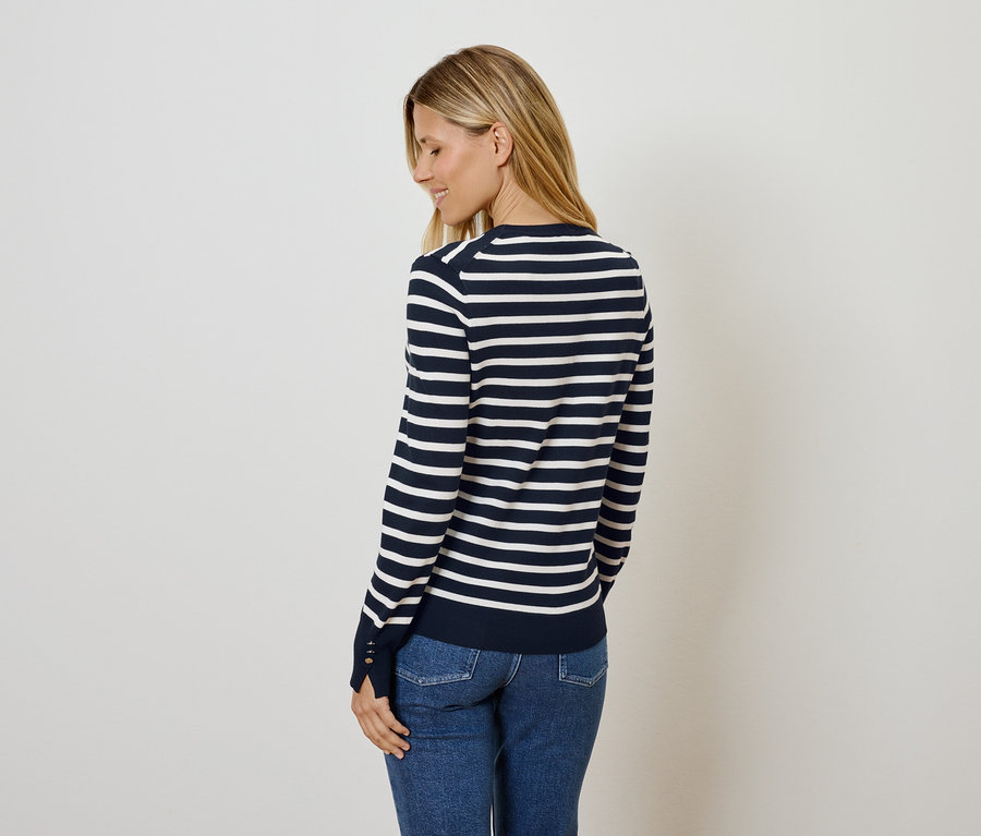 Frau posiert in einem blau-weiß gestreiften Pullover und Jeans.
