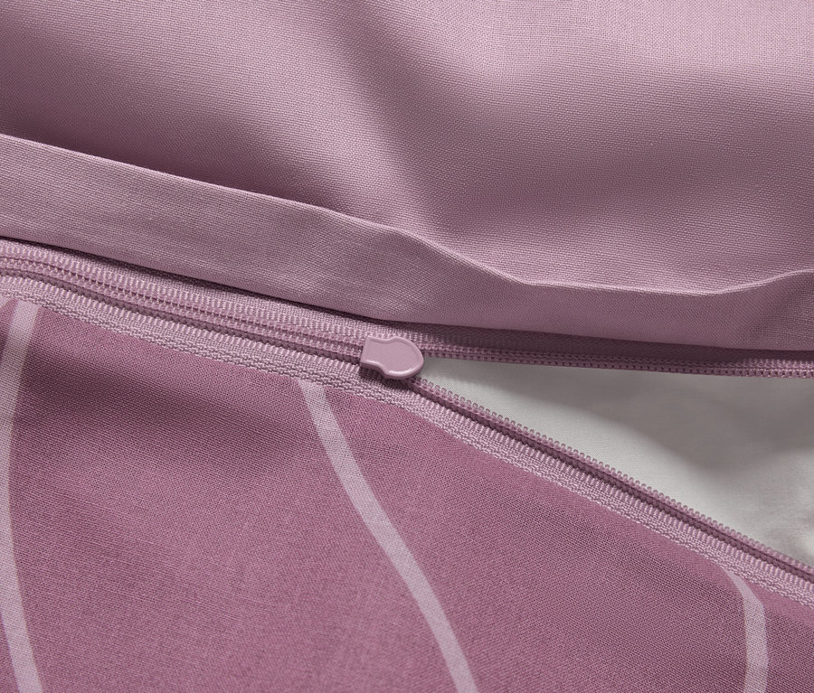 Detailaufnahme eines lila Bettbezugs mit Reißverschluss und weißem Innenfutter.