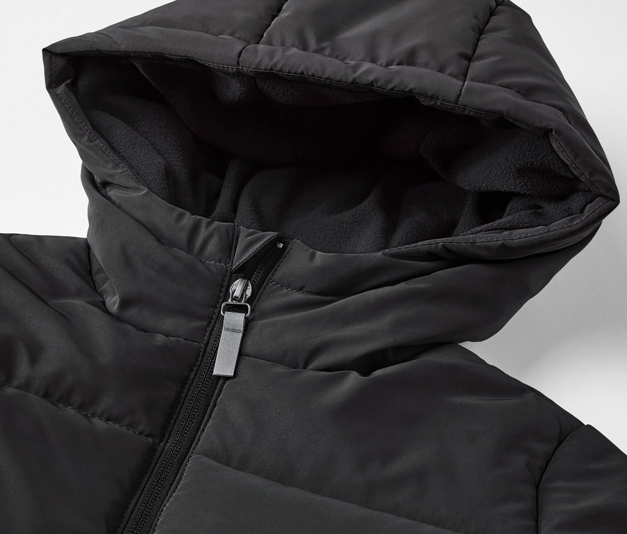 Detailaufnahme einer schwarzen Kinder-Steppjacke mit reflektierenden Elementen.