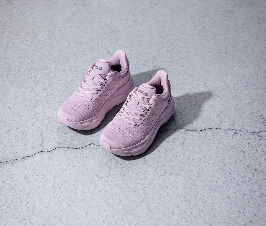 Zwei lilafarbene Fila-Laufschuhe stehen auf einem grauen Untergrund.