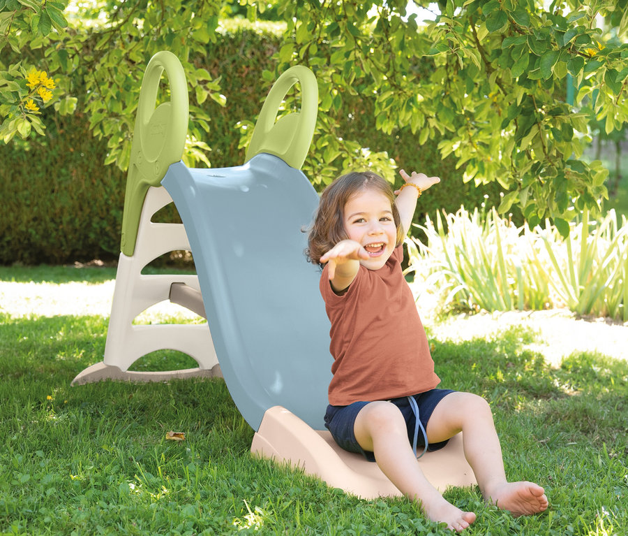 Lachendes Mädchen sitzt am Ende der Smoby Life Rutsche »GM« mit Wasseranschluss und streckt die Arme aus.