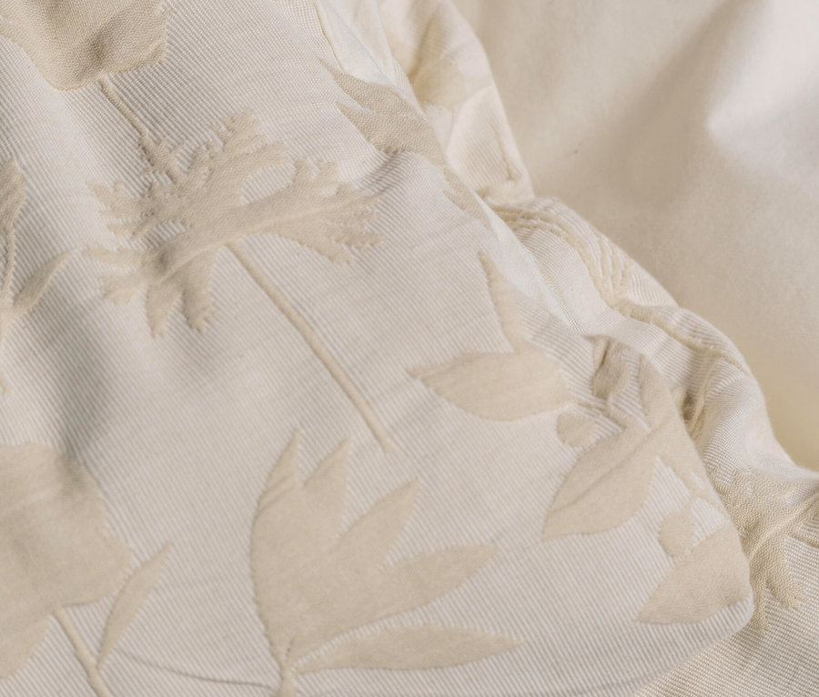 Nahaufnahme von beigem Stoff mit Blattmuster.