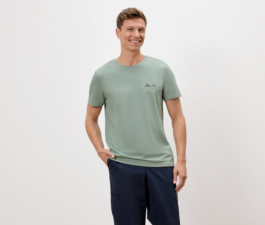 Mann mit hellgrünem T-Shirt und blauen Shorts vor weißem Hintergrund.