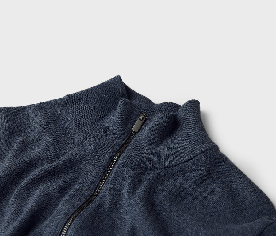 Nahaufnahme eines marineblauen Strickpullovers mit Reißverschluss und Stehkragen.