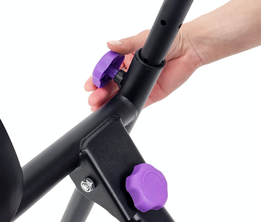 Eine Hand justiert einen lila Knopf an einem schwarzen Trainingsgerät.