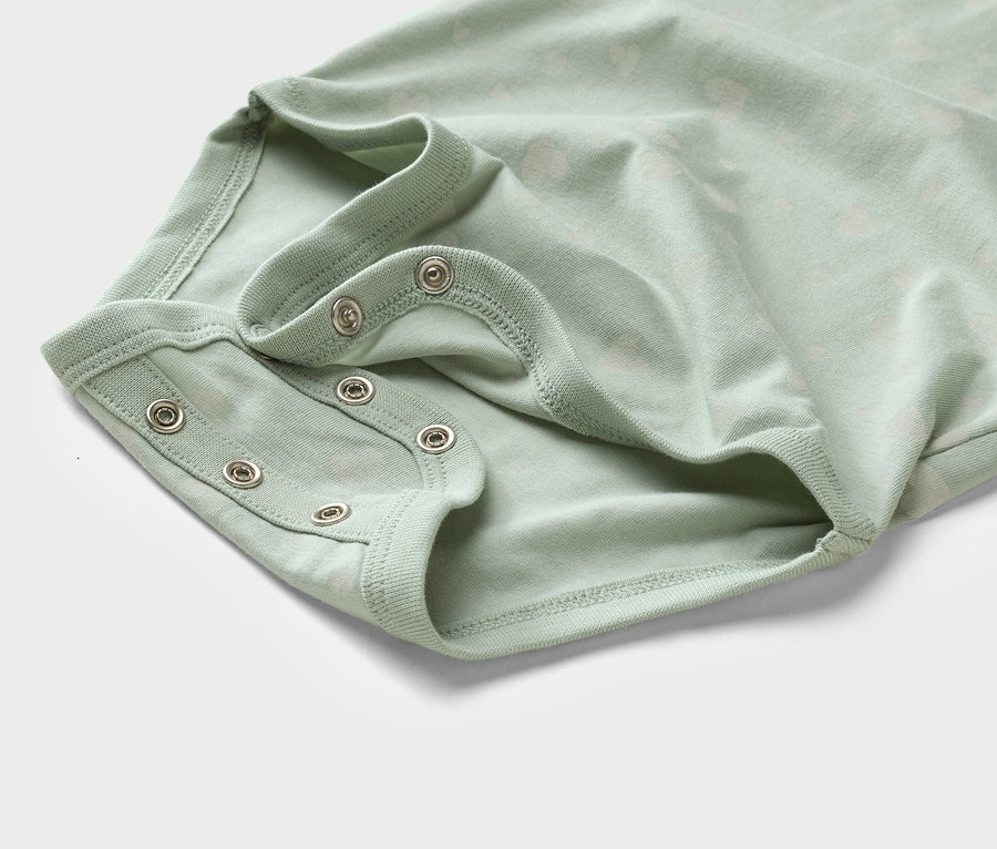 Nahaufnahme eines hellgrünen Babybodys mit Druckknöpfen.