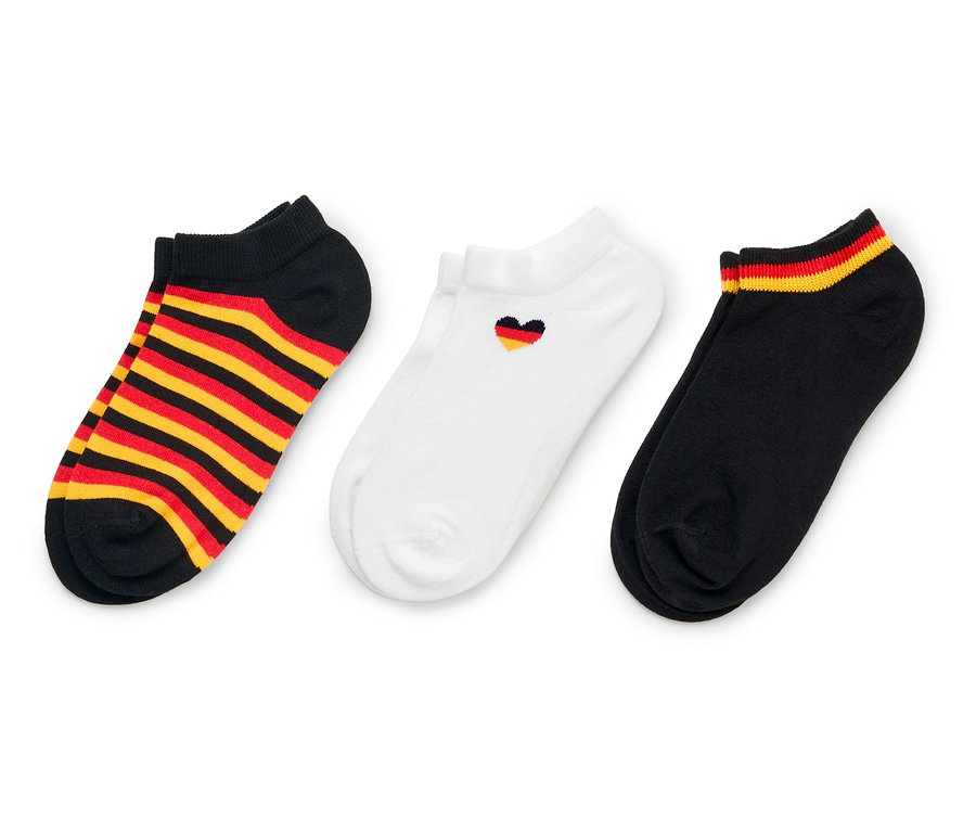 Drei Socken liegen auf einem weißen Hintergrund. Eine Socke ist schwarz mit rot-goldenen Streifen, eine ist weiß mit einem kleinen Herz und eine ist schwarz mit rot-goldenen Streifen am Rand.
