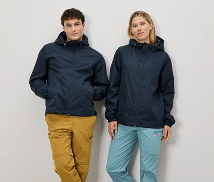 Ein Mann und eine Frau stehen nebeneinander und tragen marineblaue Regenjacken und Outdoor-Hosen.