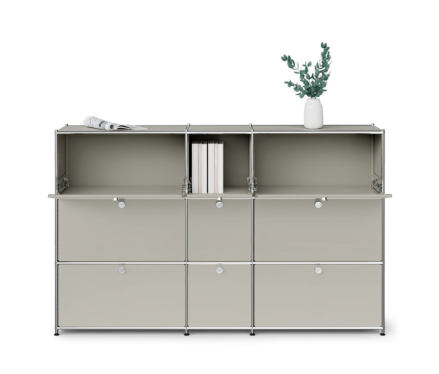 Ein hellgraues, modulares Schranksystem mit Chromrahmen. Die drei oberen Fächer sind nach unten geöffnet und zeigen eine Zeitung, Bücher und eine Vase mit Pflanzen. Die mittleren und unteren Fächer haben geschlossene Türen mit Chromgriffen.