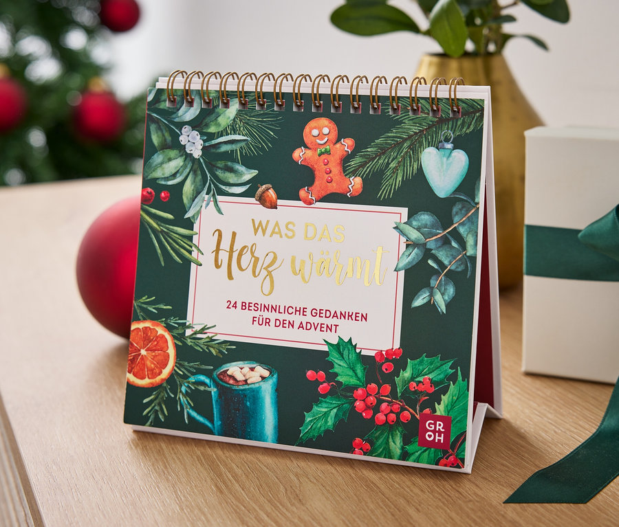 Tischkalender mit Weihnachtsmotiv und Geschenkbox mit grünem Band auf einem Tisch.