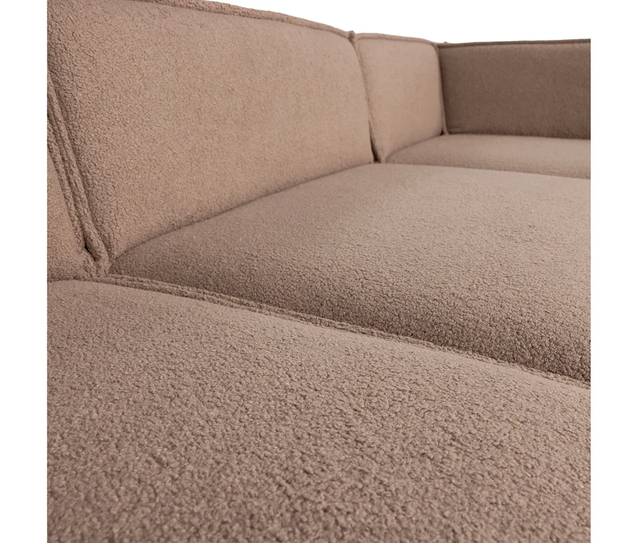 Nahaufnahme eines hellbraunen Ecksofas, das mit einem strukturierten Bouclé-Stoff bezogen ist und Sitz- und Rückenpolster mit sichtbaren Nähten zeigt.