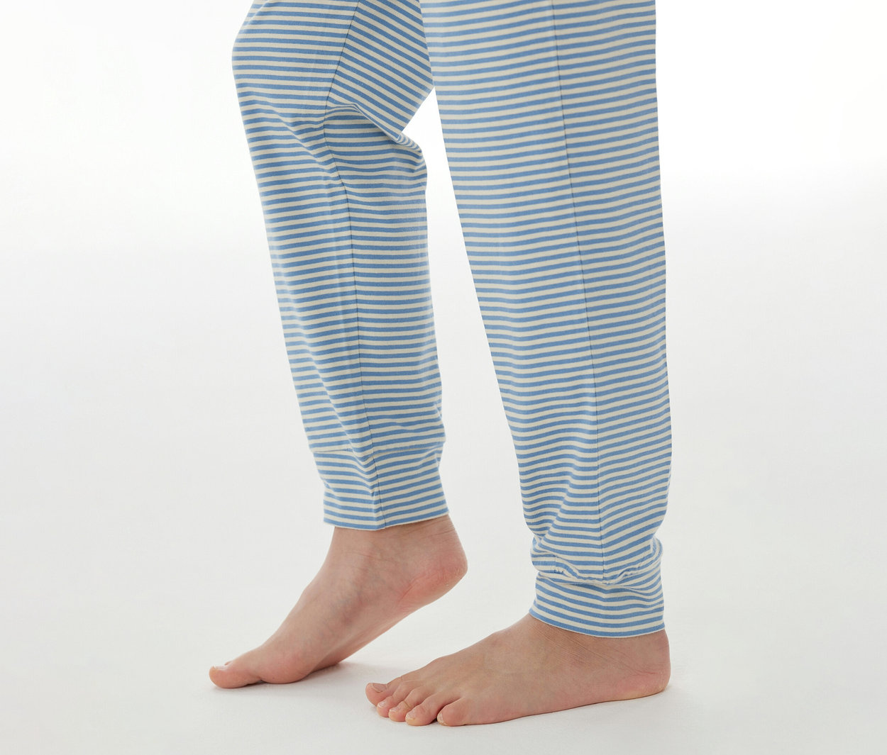 Unterschenkel und nackte Füße einer Person, die eine blau-weiß gestreifte SCHIESSER Kinder-Pyjamahose trägt.