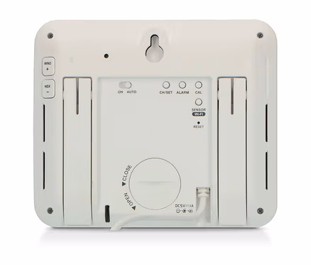 Rückseite eines weißen, rechteckigen elektronischen Geräts mit Aufhängeöse, Tasten für Wind, NDX, CH/SET, Alarm, Kalibrierung, Sensor Wi-Fi und Reset, einem Ein/Auto-Schalter, einem runden Batteriefachdeckel und einem angeschlossenen DC 5V-Stromkabel.
