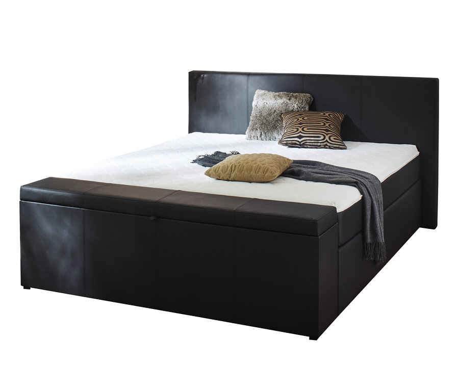 Schwarzes Boxspringbett mit Stauraum und Bettbank. Auf dem Bett liegen zwei Kissen und eine graue Decke.
