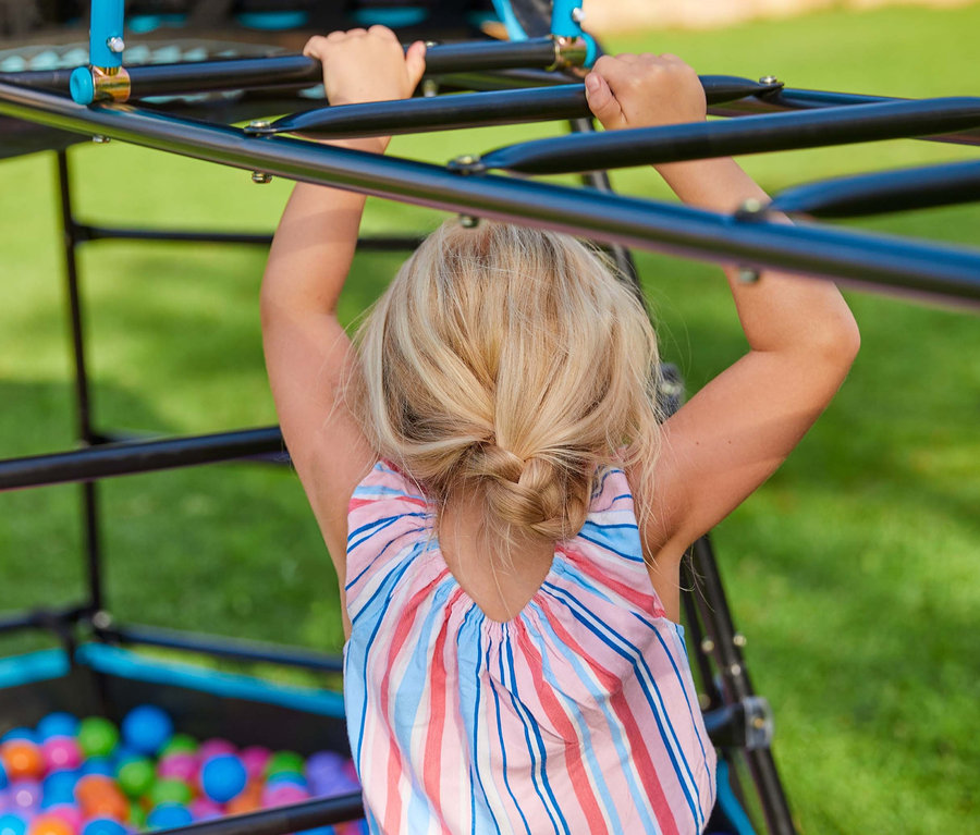 Mädchen klettert auf Kletterturm »Explorer« mit Zelt.