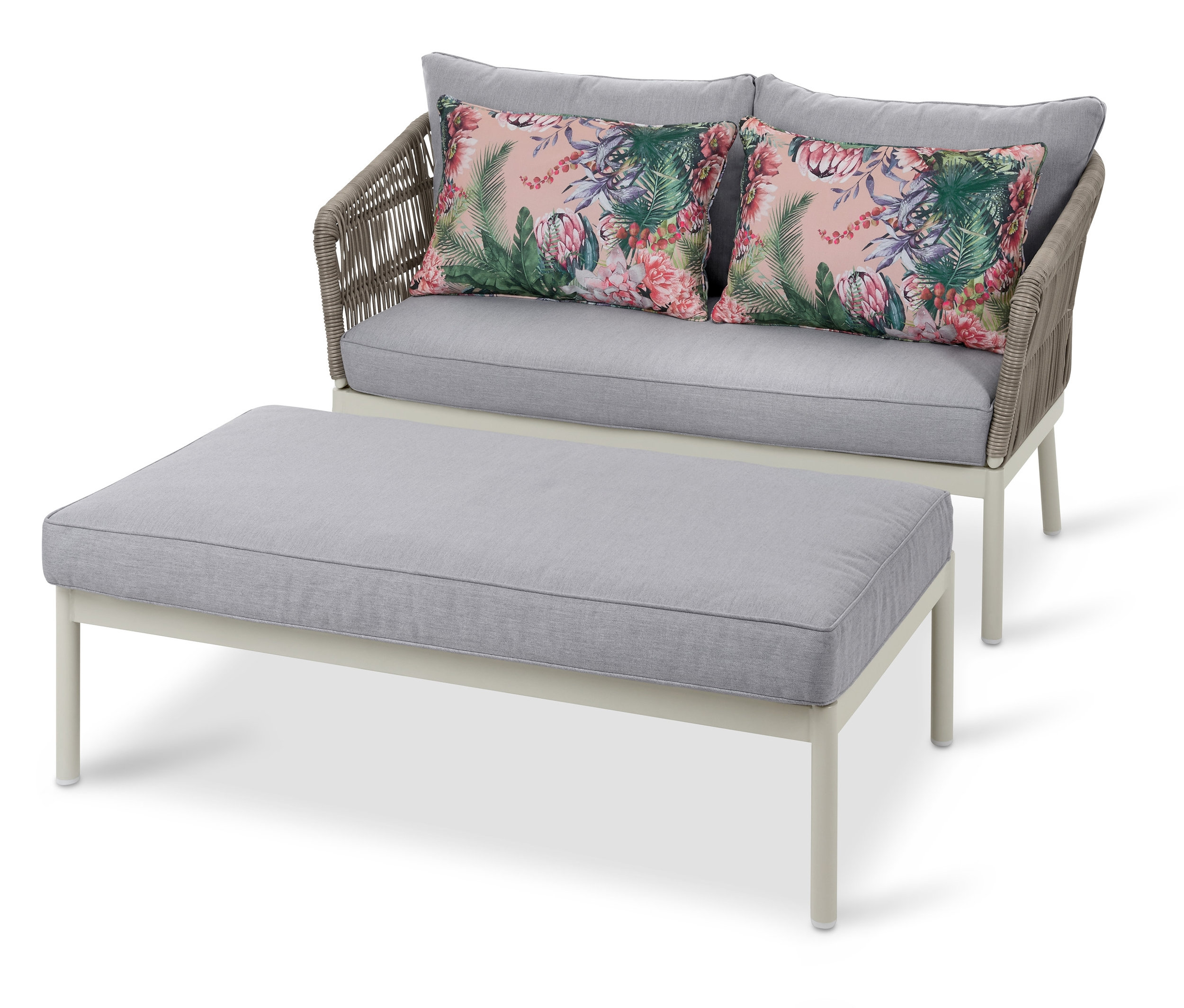 Ein Outdoor-Loungesofa mit Fußbank und zwei Kissen mit Blumenmuster.