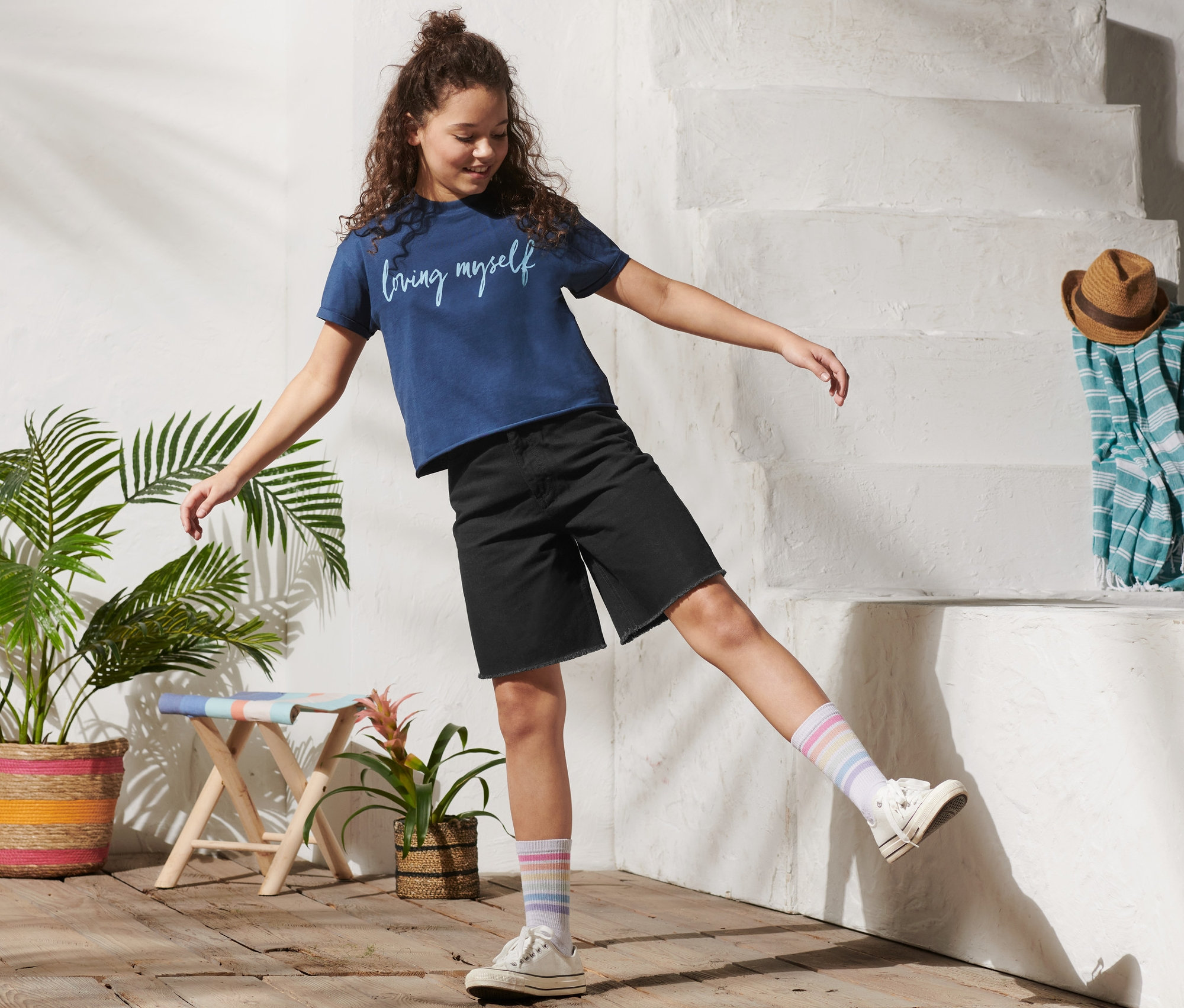 Mädchen posiert in Bermuda-Shorts.