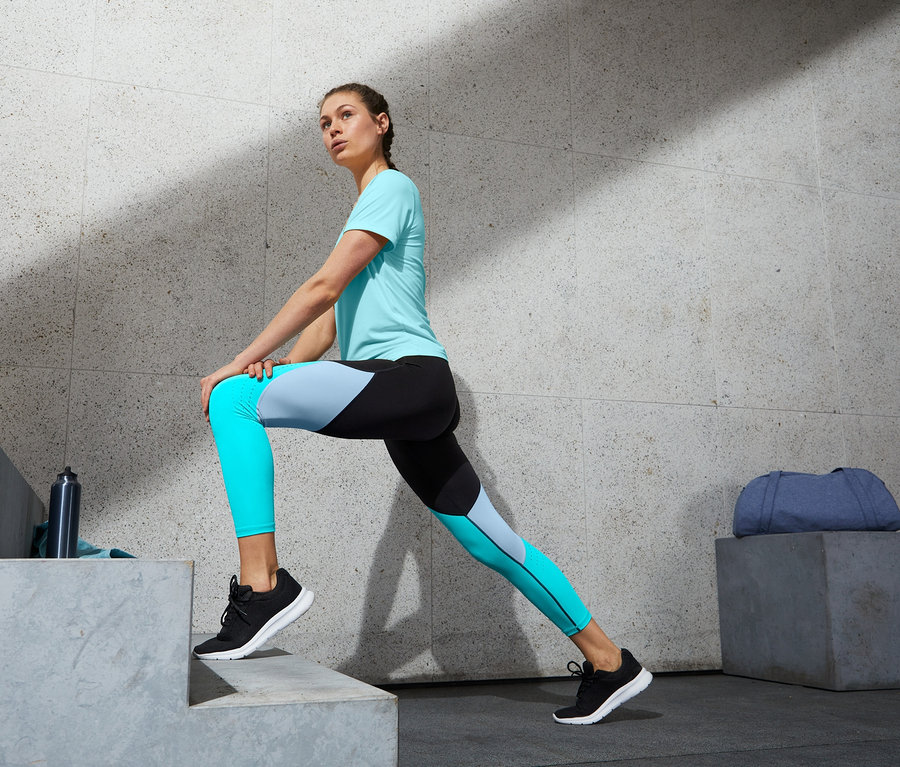 Eine Frau dehnt ihr Bein auf Stufen und trägt eine 7/8-Sporttight.