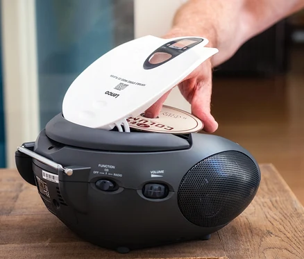 Mann legt CD in weißen Lenco »SCD-24 Boombox« CD-Player mit Radio ein.