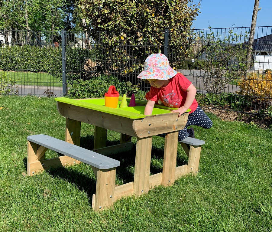 Mädchen spielt am Wendi Picknick- und Matschtisch mit Bänken.