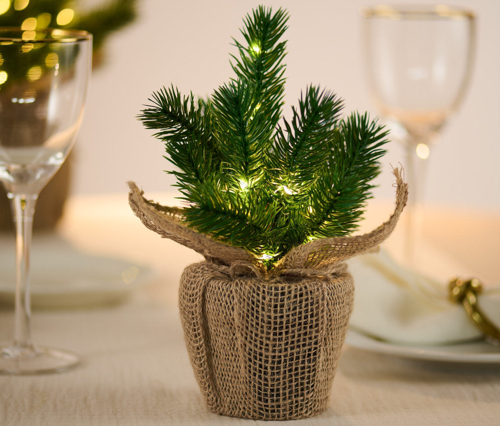 Kleiner LED-Tannenbaum steht auf einem Tisch.