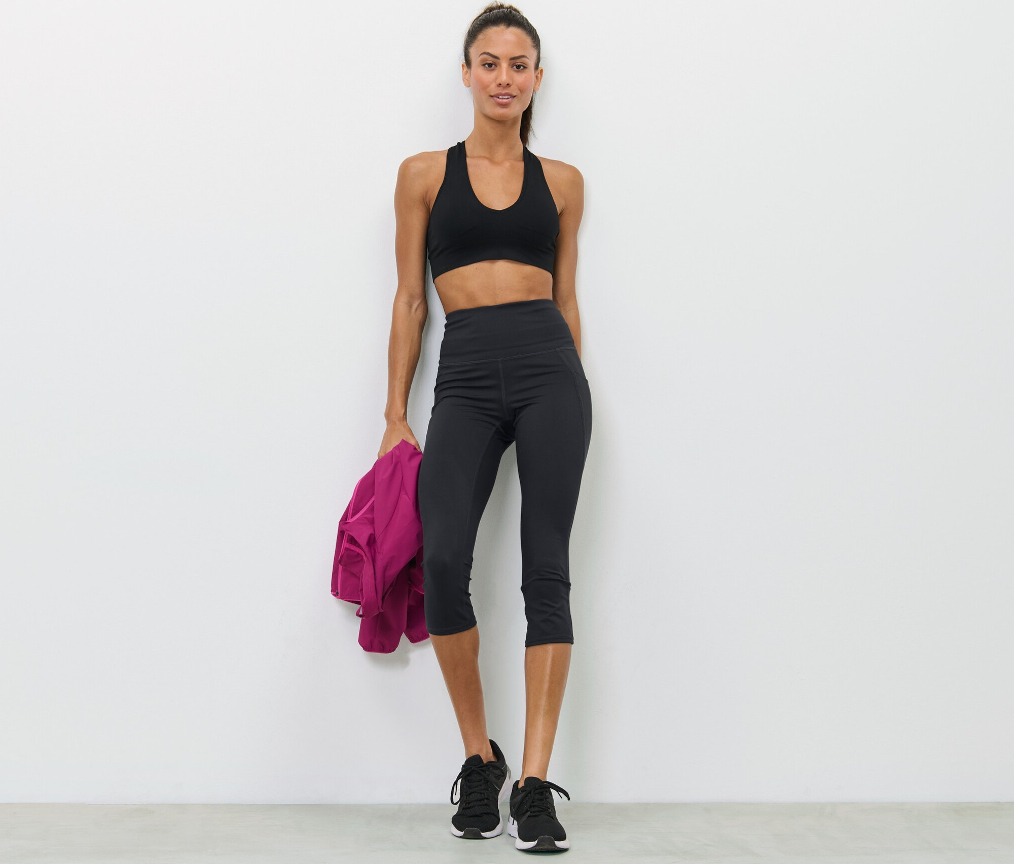 Frau posiert in Sport-BH und schwarzer 3/4-Sporttight.