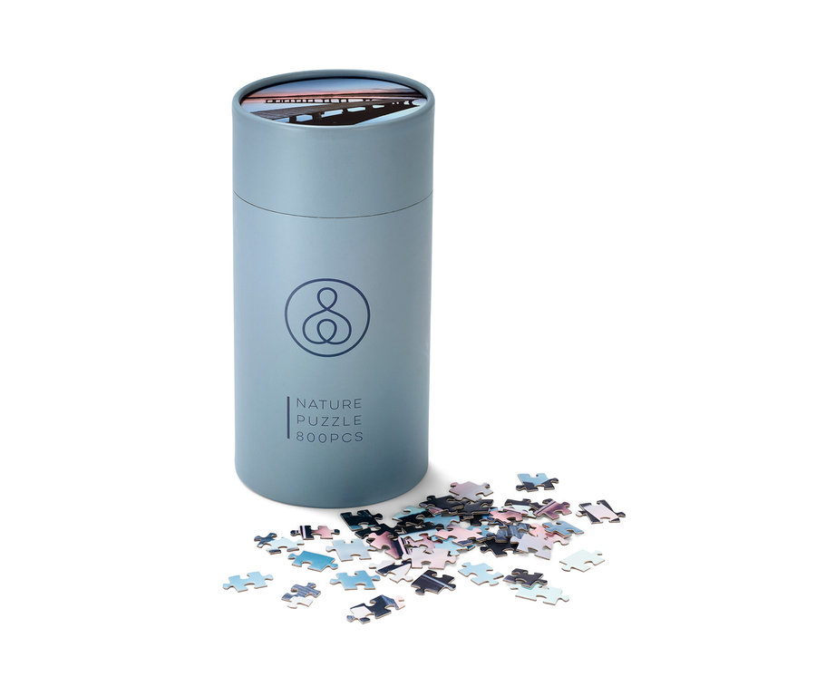 Eine blaue Puzzle »Steg«-Packung und verstreute Puzzleteile.