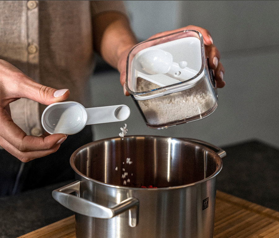 Frau schüttet Gewürze aus einem ZWILLING FRESH & SAVE CUBE, Starter-Set, M, 5-teilig in einen Topf.