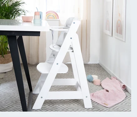 Weißer roba Treppenhochstuhl »Sit Up Flex« steht in einer Ecke des Zimmers neben einem Tisch.