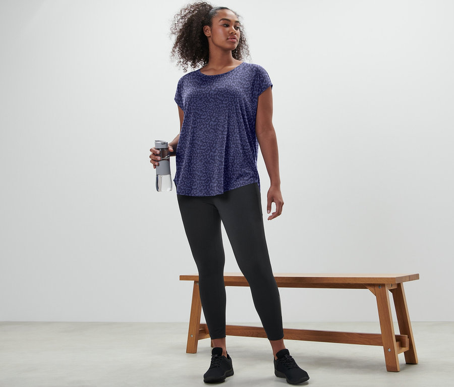 Frau hält lila Sportshirt und Wasserflasche.