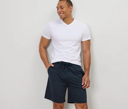 Mann steht mit der Hand in der Tasche der Relaxshorts.