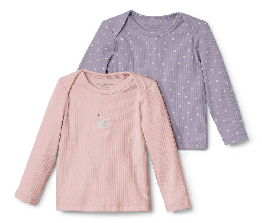 Zwei Baby-Langarmshirts mit Rippstruktur, eines rosa mit Schwan-Applikation, das andere lila mit Punkten.