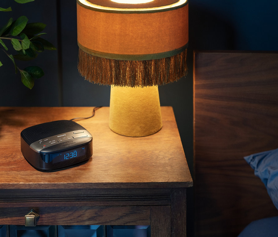 Nachttisch mit Lampe und Philips Radiowecker »TAR3505«. Die Uhrzeit 12:38 ist auf dem Radio zu sehen.