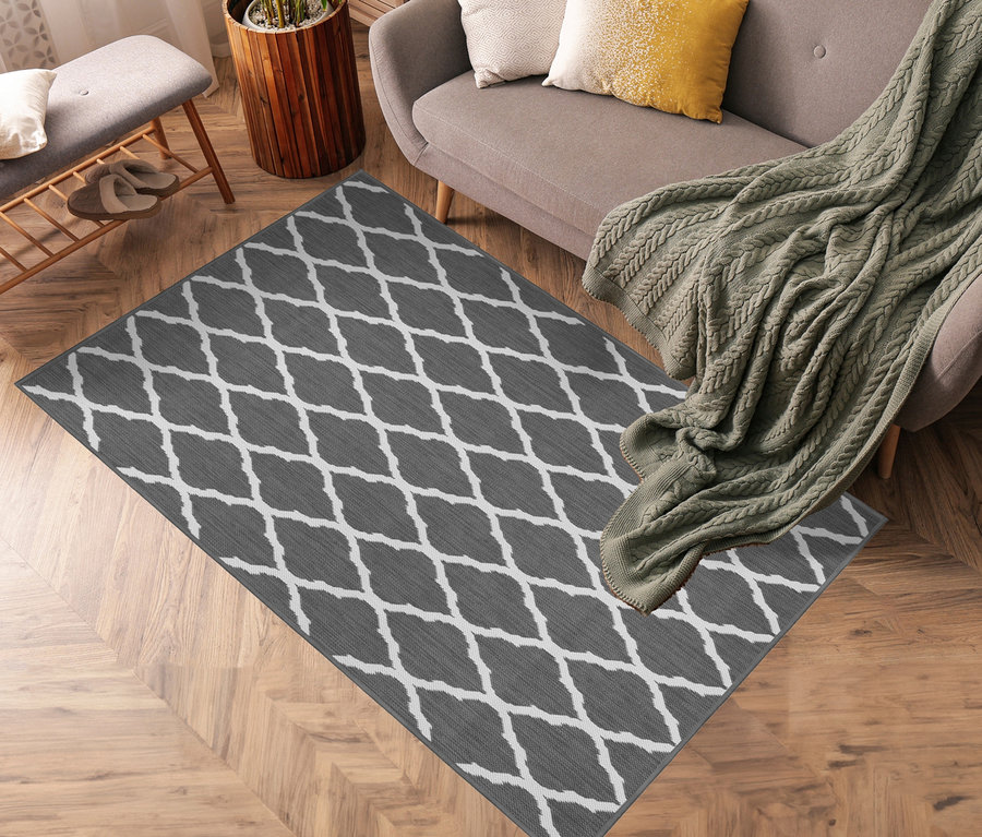 Grauer Outdoor-Wende-Teppich »Rhombus« mit weißem Rautenmuster auf Holzboden im Wohnzimmer.