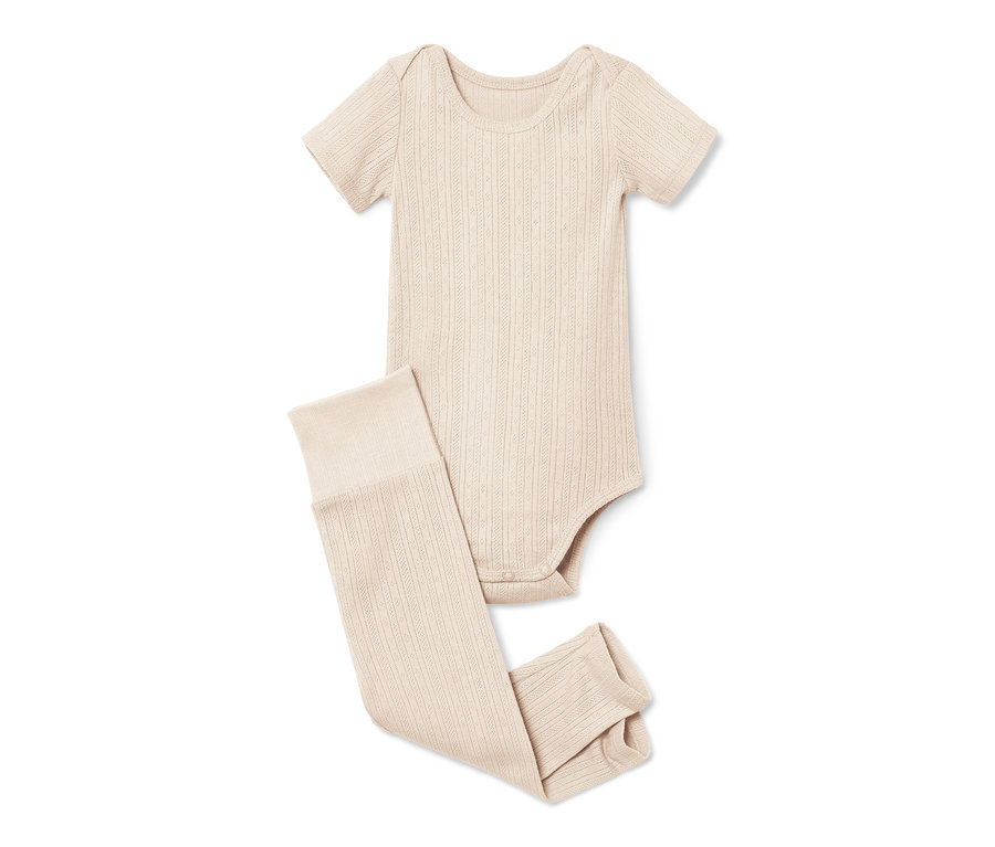 Ein beiger Baby-Body und Leggings liegen auf einem weißen Hintergrund.