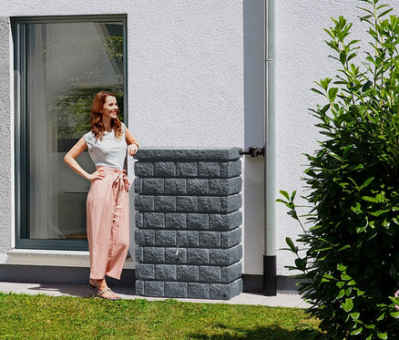 Eine Frau lehnt an einem Garantia Wandtank-Komplett-Set »ROCKY Junior«, ca. 300 l, graphit-grau.