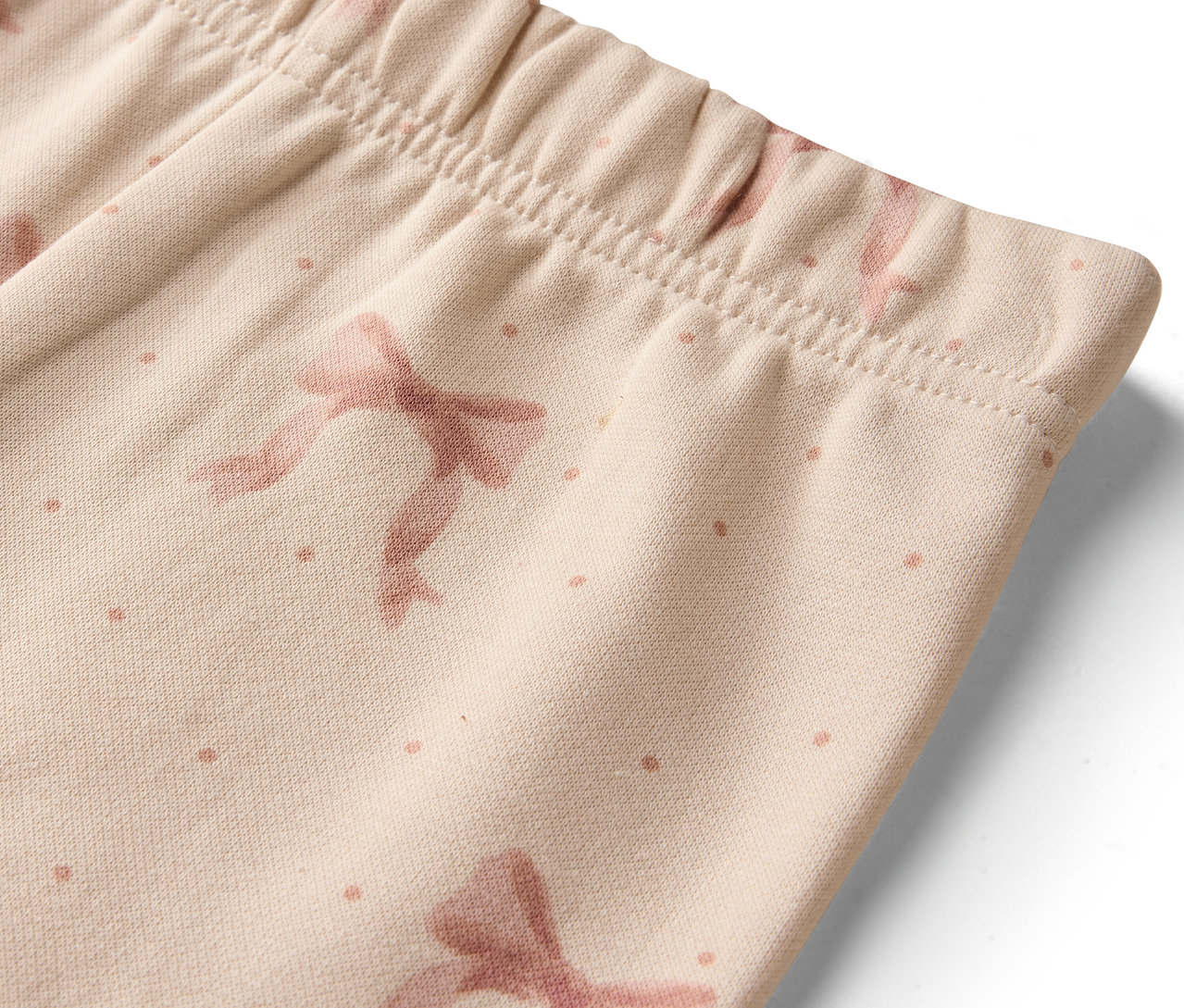 Detail einer beigen Leggings mit Schleifen und Punkten.