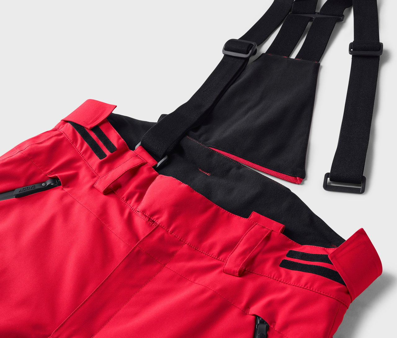 Detail einer roten Skihose mit schwarzen Hosenträgern.