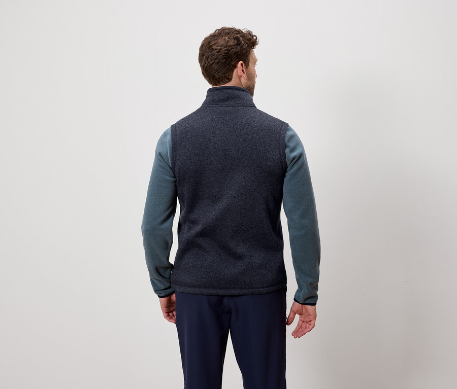 Mann von hinten trägt eine dunkelblaue Weste und einen blauen Pullover.