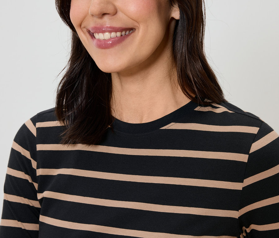 Lächelnde Frau mit dunklem Haar trägt ein gestreiftes T-Shirt.