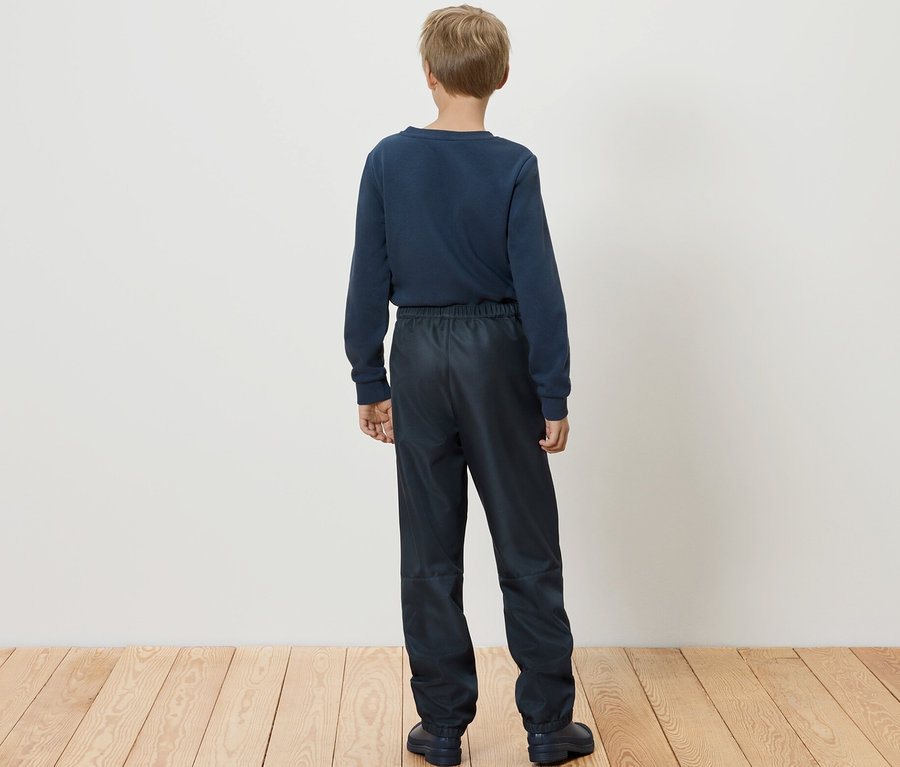 Ein Junge steht mit dem Rücken zum Betrachter und trägt eine Kinder-Softshellhose.